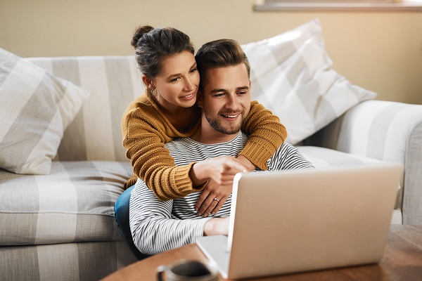 A young married couple sit together while reviewing their digital assets on a laptop computer.